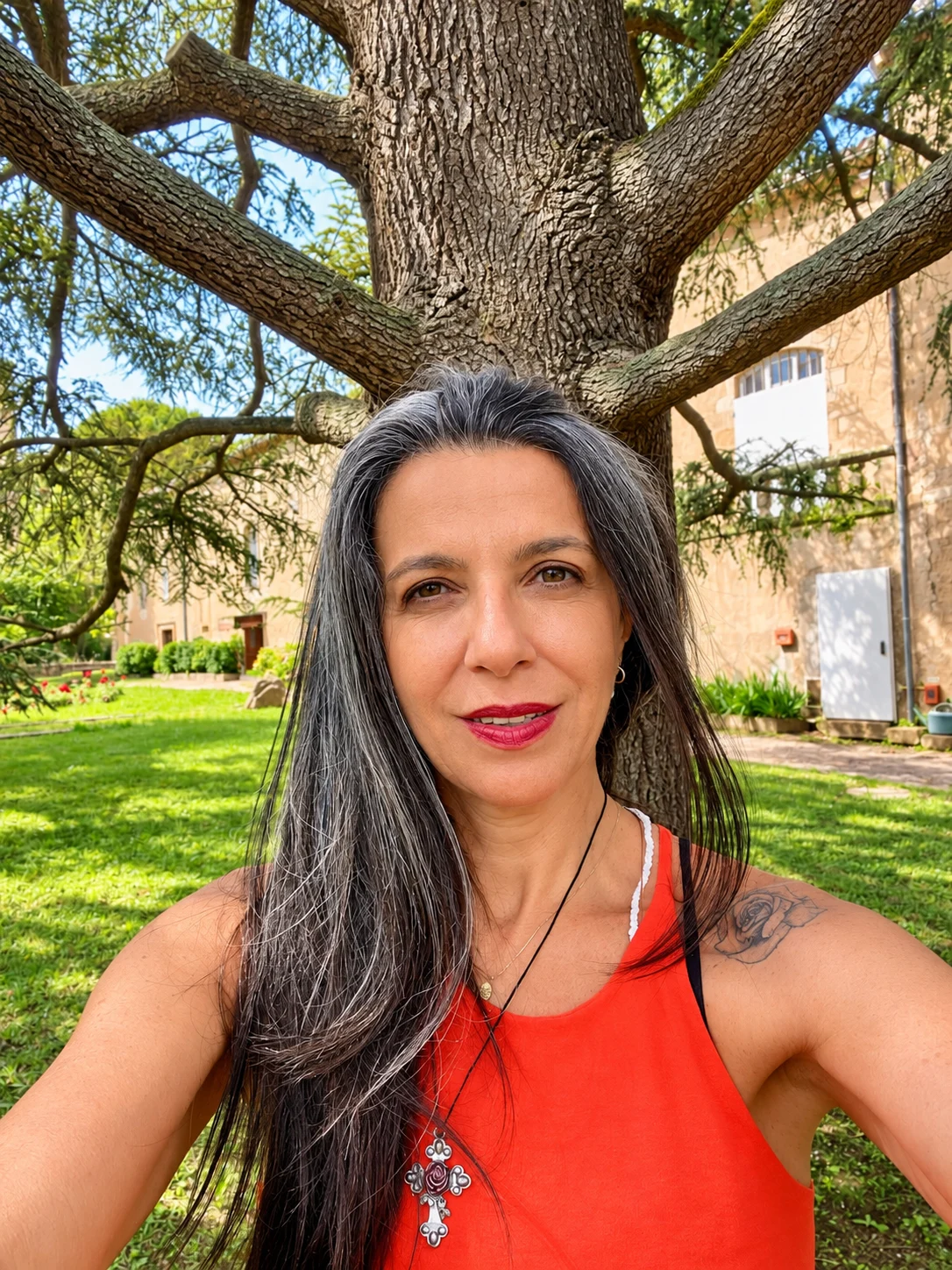 Adriana à sombra de uma árvore, em um jardim.