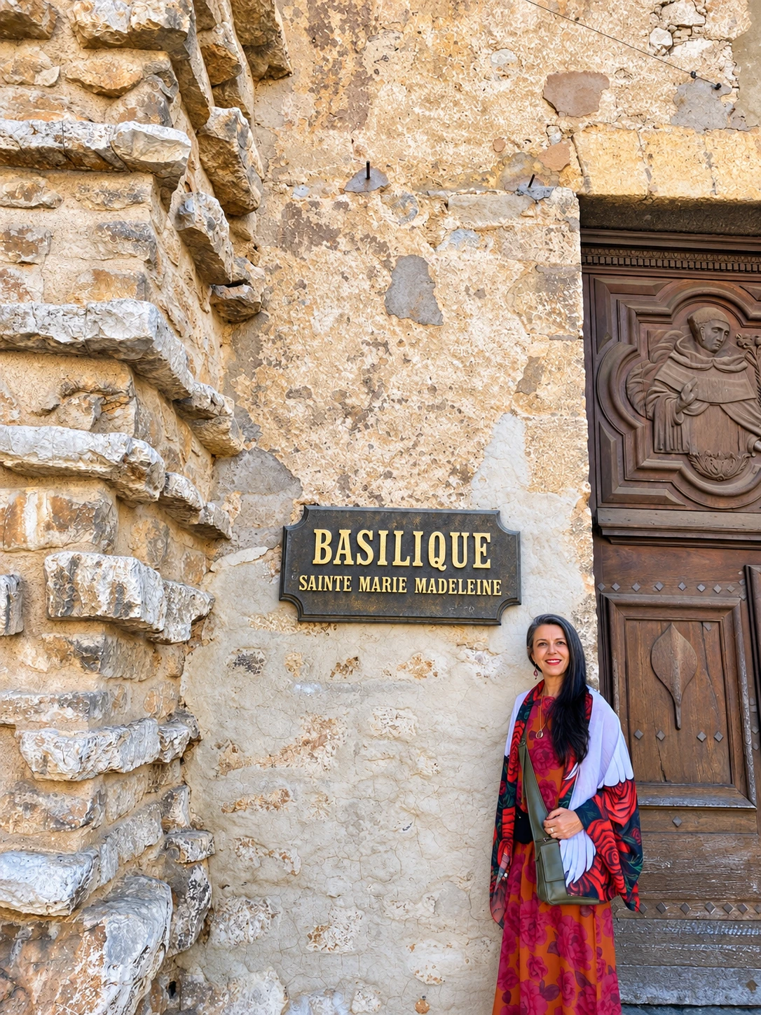 Adriana à entrada de uma basílica, junto a uma parede de pedra.