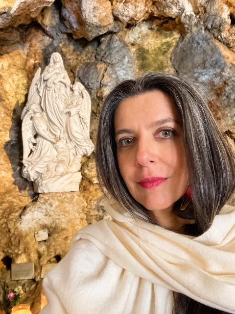 Adriana ao lado de uma imagem branca em uma gruta.