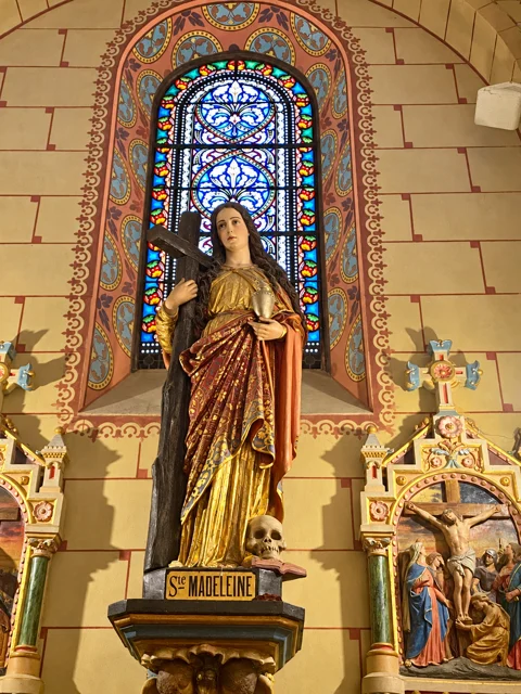 Escultura religiosa diante de um vitral.