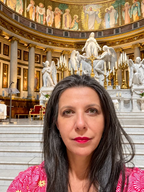 Adriana diante de um altar com esculturas e pinturas.